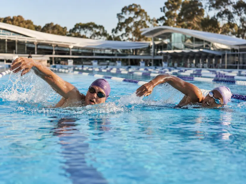 Two adult swimmers training together in a clean modern pool